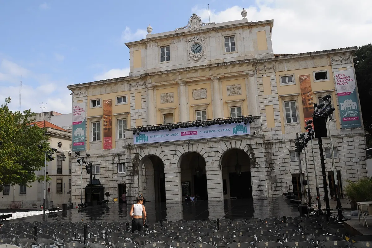 The pale yellow neoclassical facade of the Teatro Nacional de São Carlos with three arches at street level.
